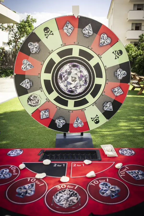 Bespoke roulette wheel of diamond, spade and joker panels above a red gaming table