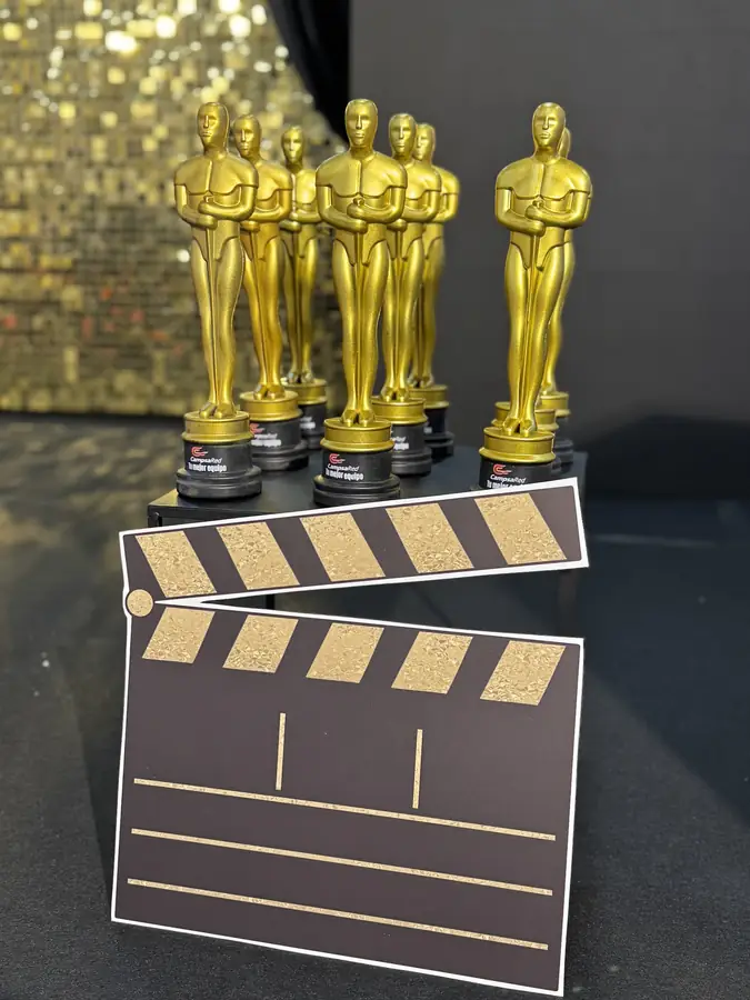 Gold award trophies and a clapperboard resting on gold sequins