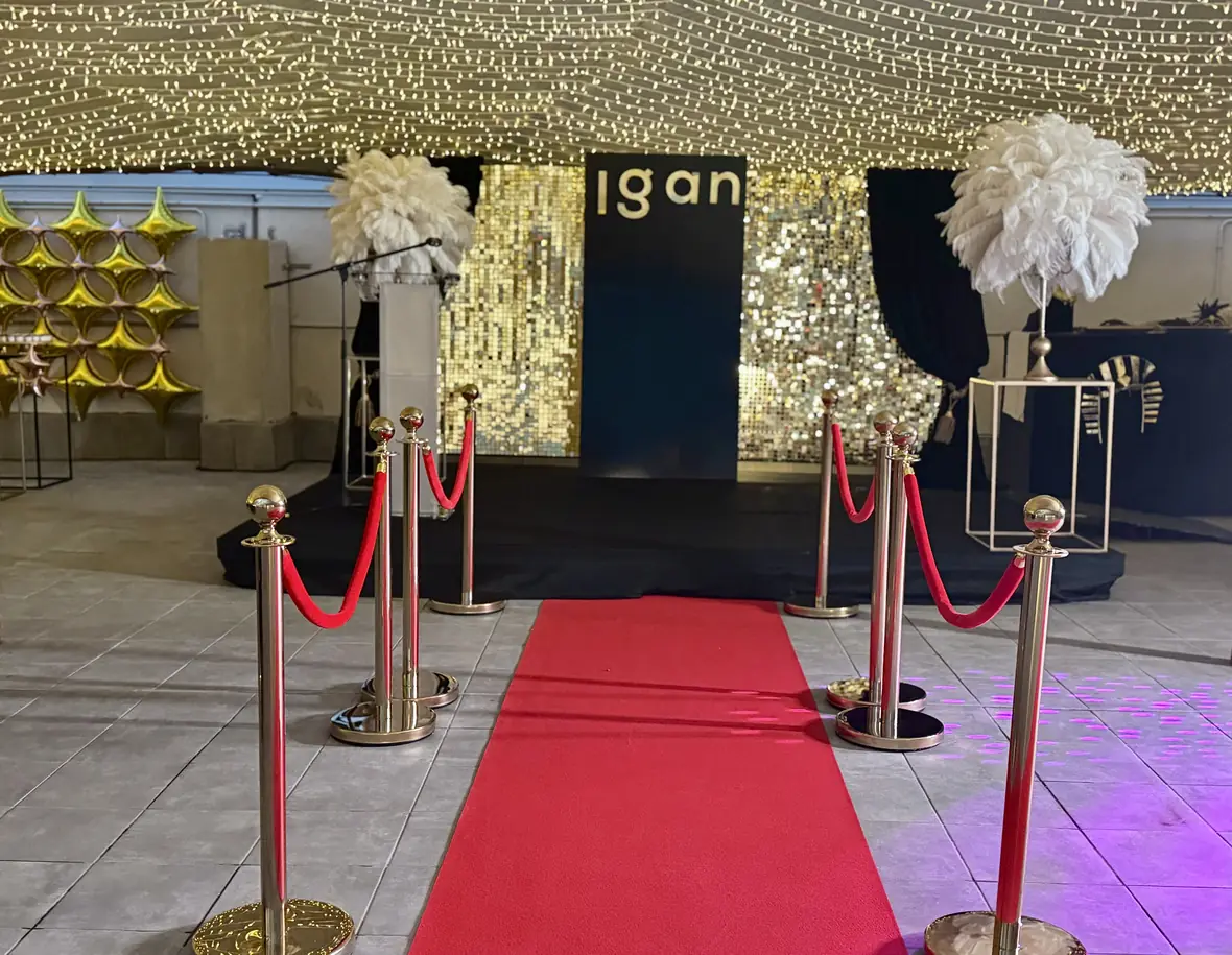 Red carpet entrance with gold sequin backdrop and ostrich-feather columns at the Igan gala