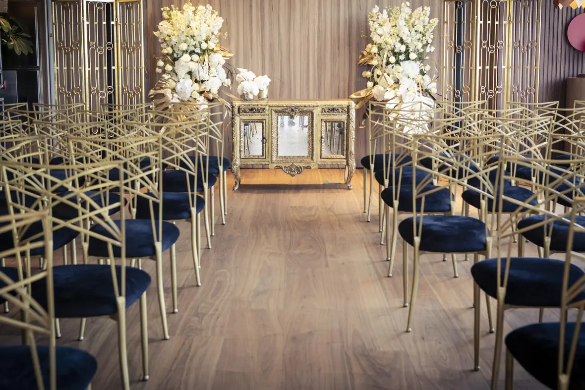 Ceremony room with gilded chiavari chairs, navy velvet and white orchids