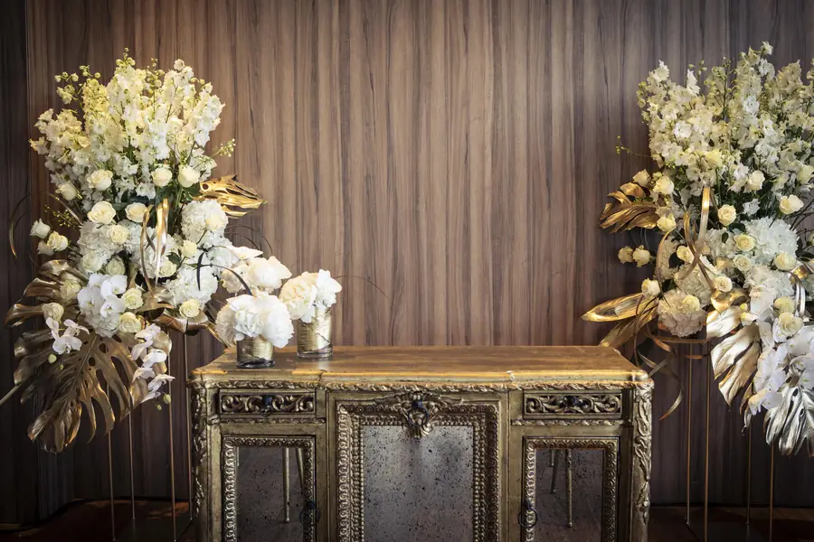 White and gold floral arrangements on gilded consoles