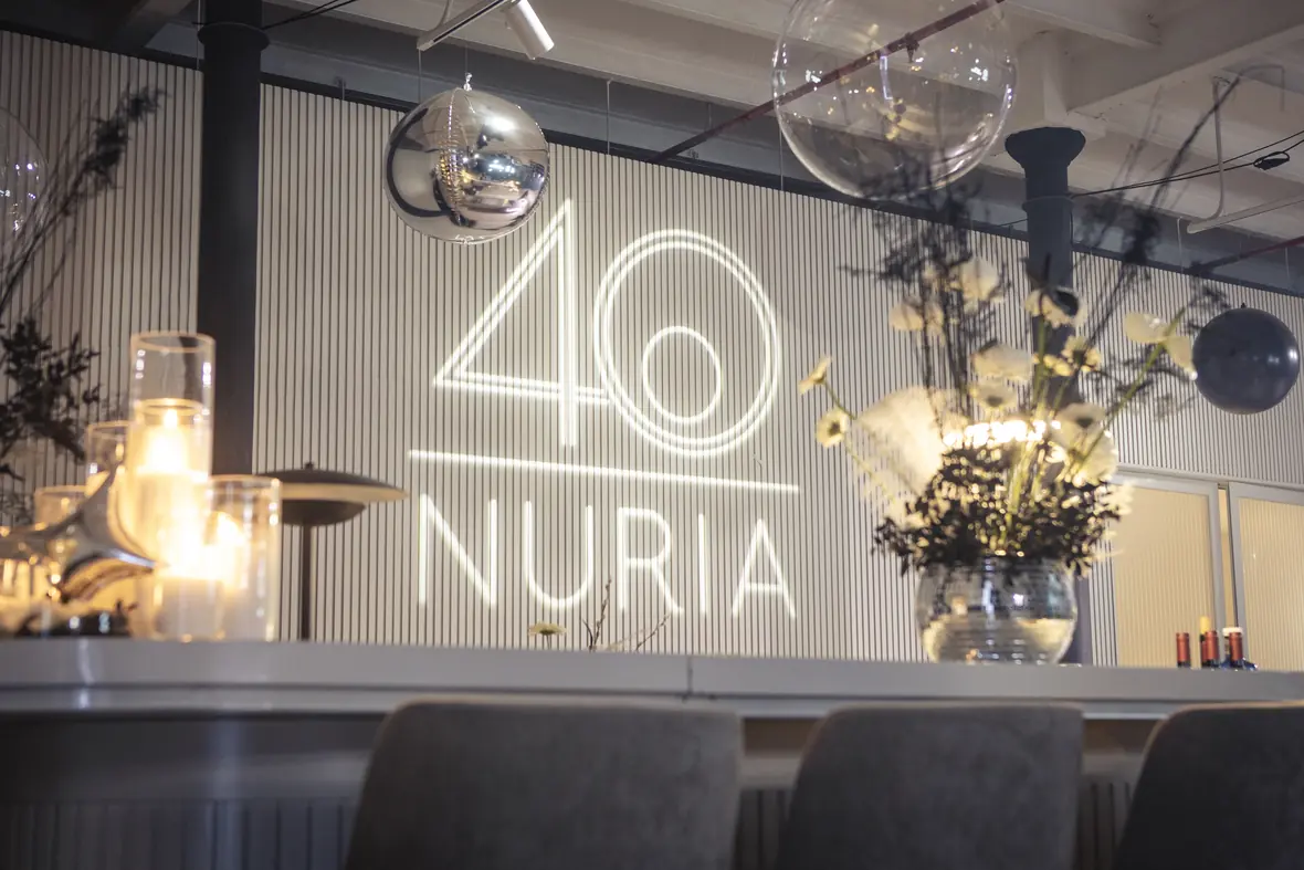 Curved white bar dressed with candles, silver stars and rows of glasses beneath the 40 Nuria sign