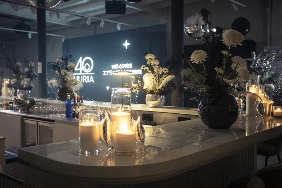 Dramatic dark floral installation glowing beneath a wall of warm fairy lights