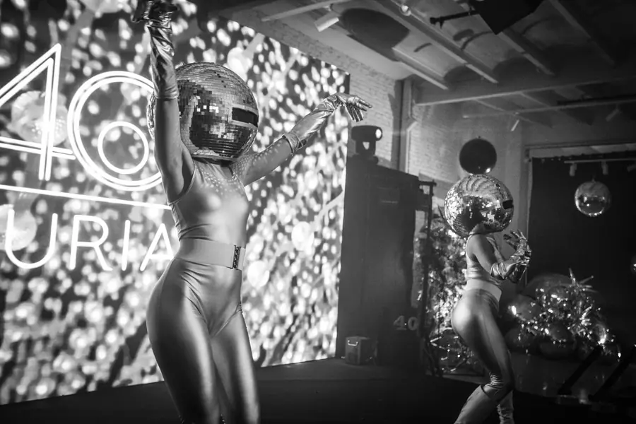 A silver performer against a glowing wall of light, in black and white