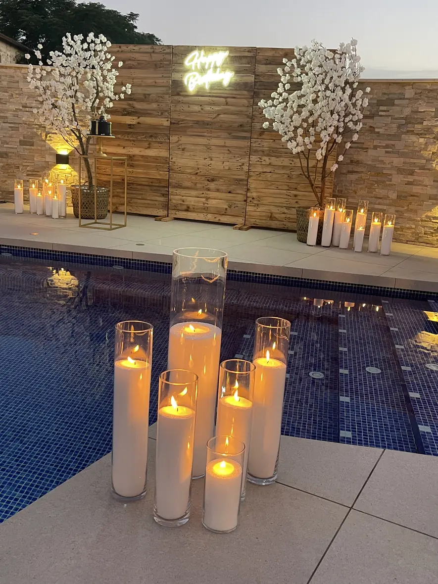 Candlelight glowing on the edge of a blue pool at dusk