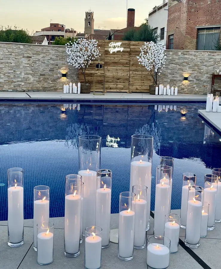 Swimming pool lined with dozens of white candles at twilight