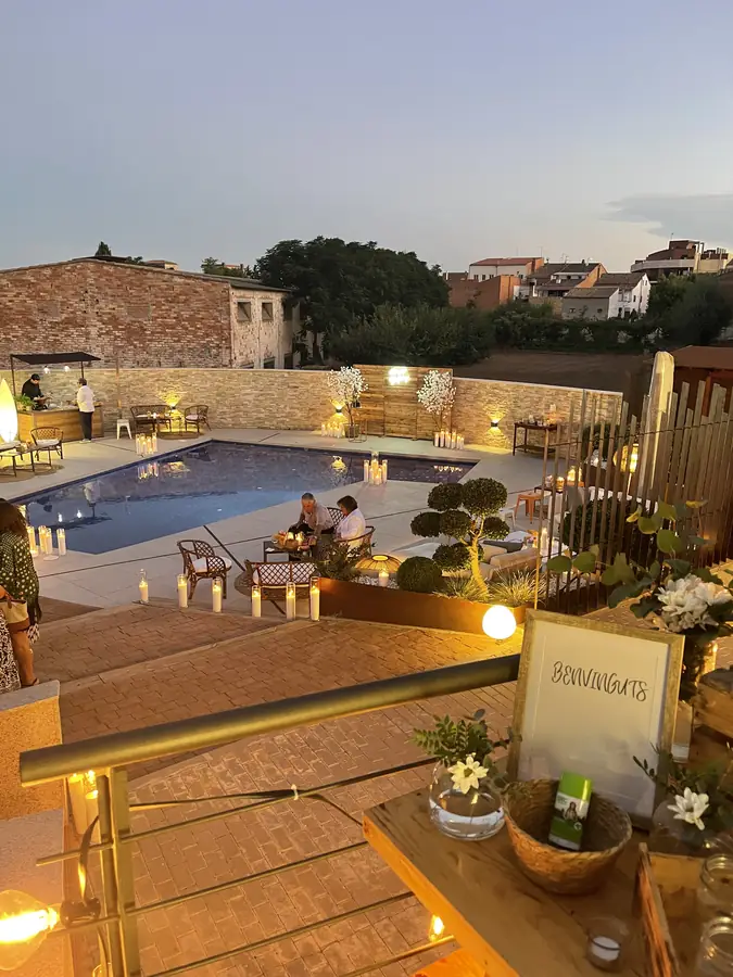 Warm-lit welcome table on a villa terrace at dusk overlooking the pool