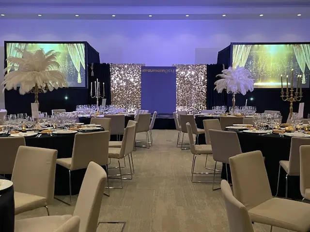 Gatsby ballroom with a gold sequin backdrop, white feather centerpieces and banquet tables