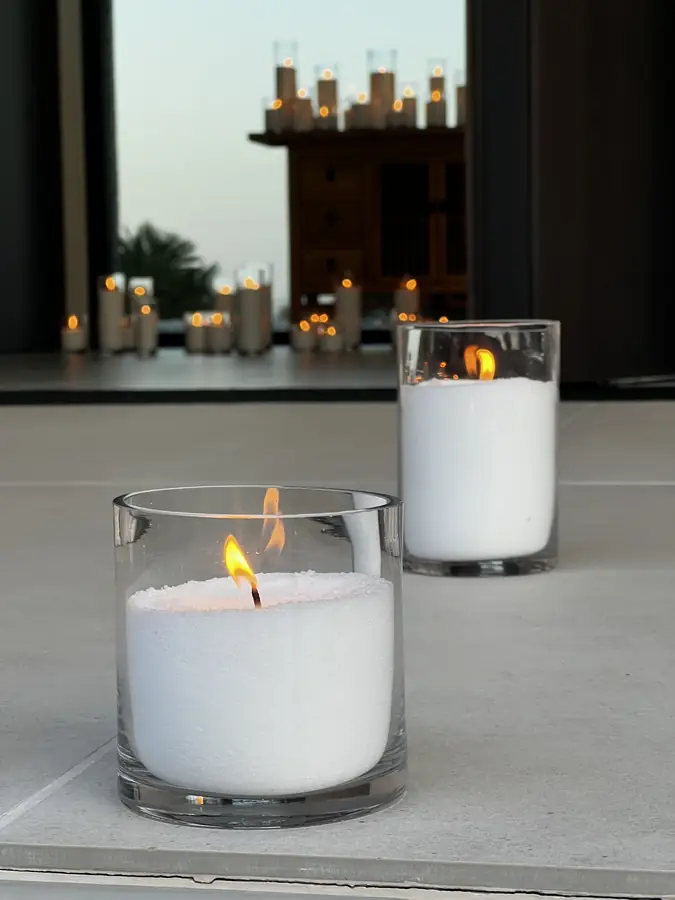 Single white pillar candle glowing in the dark