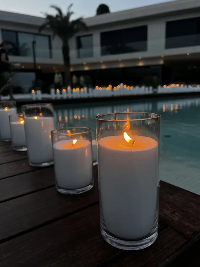 Pool lined with white pillar candles at dusk